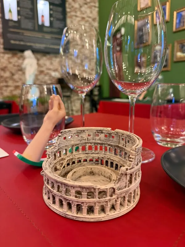 Miniatura do Coliseu sobre a mesa vermelha, entre taças de vinho