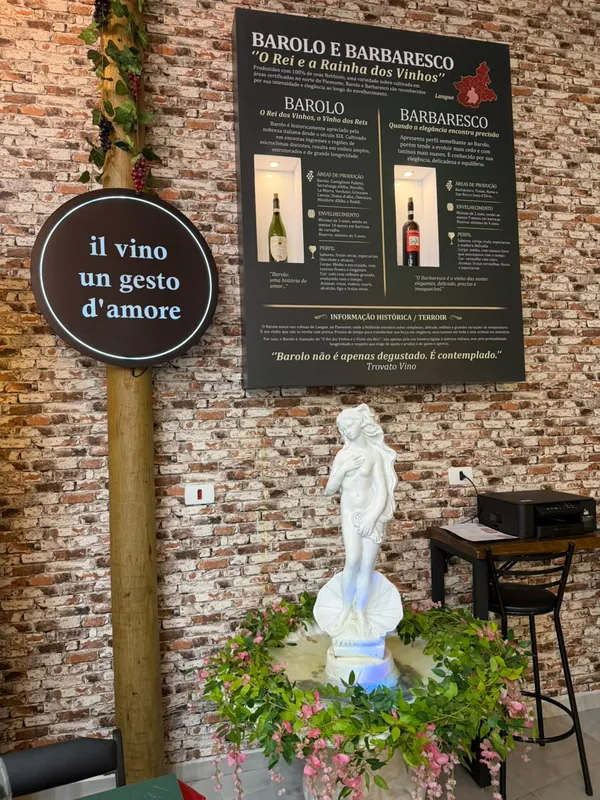 Placa “il vino un gesto d’amore”, quadro sobre Barolo e Barbaresco e uma estátua de Vênus entre flores